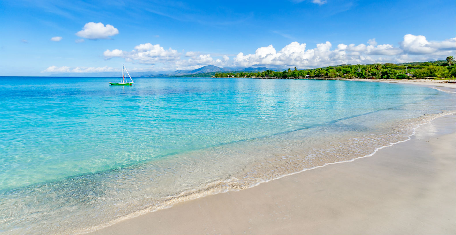 A green yacht in aqua waters just off the beach at Port Salut, Haiti