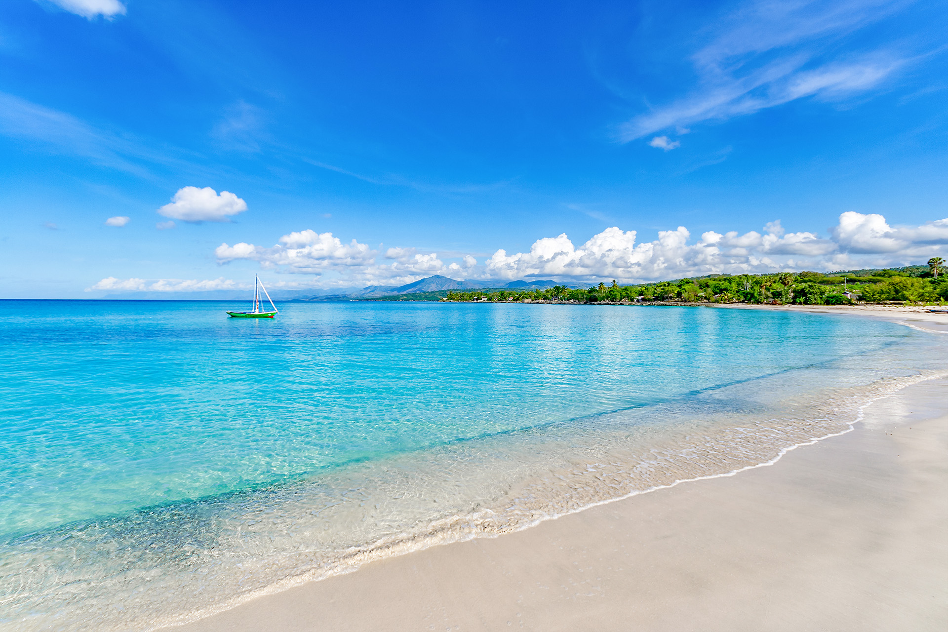 A green yacht in aqua waters just off the beach at Port Salut, Haiti