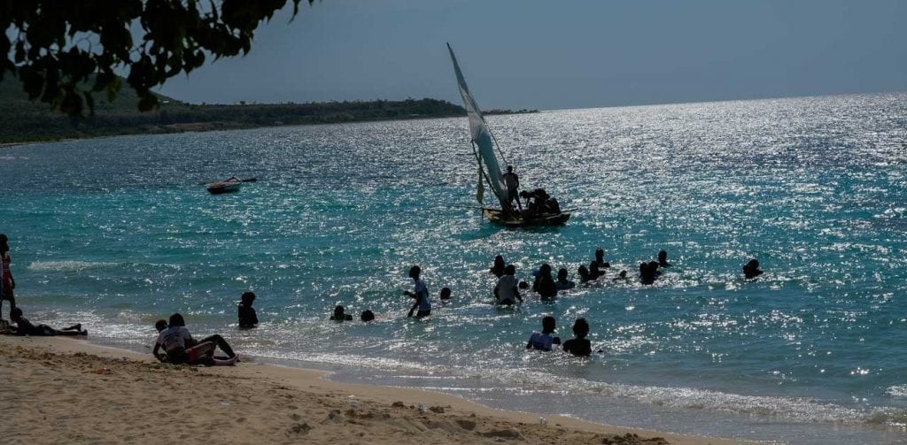 beach with people swimming and small wooden boat