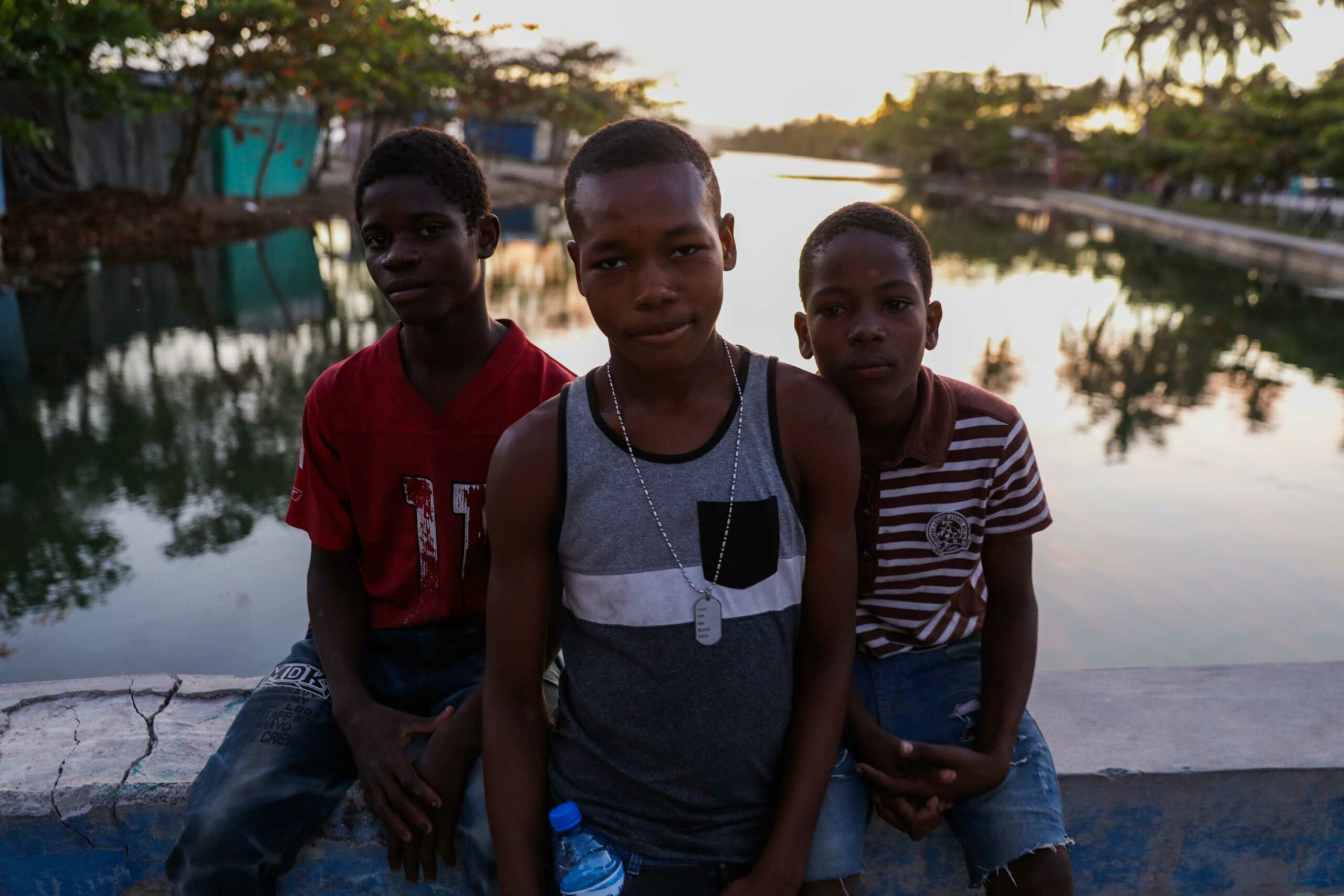 Three boys sitting on the bridge at Gelée Beach, Haiti