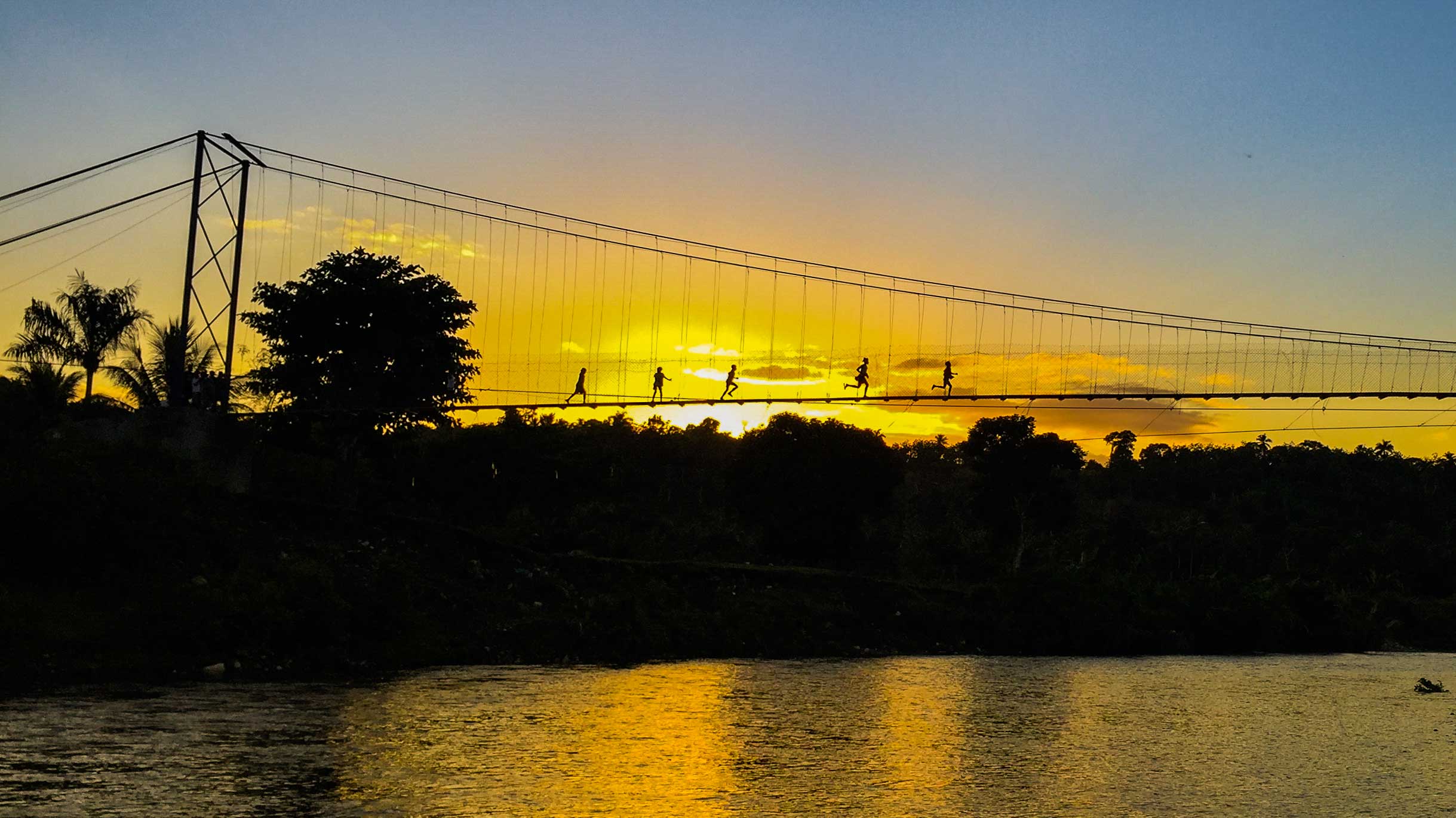 Five runners jogging over the suspension bridge in Chameau, Haiti