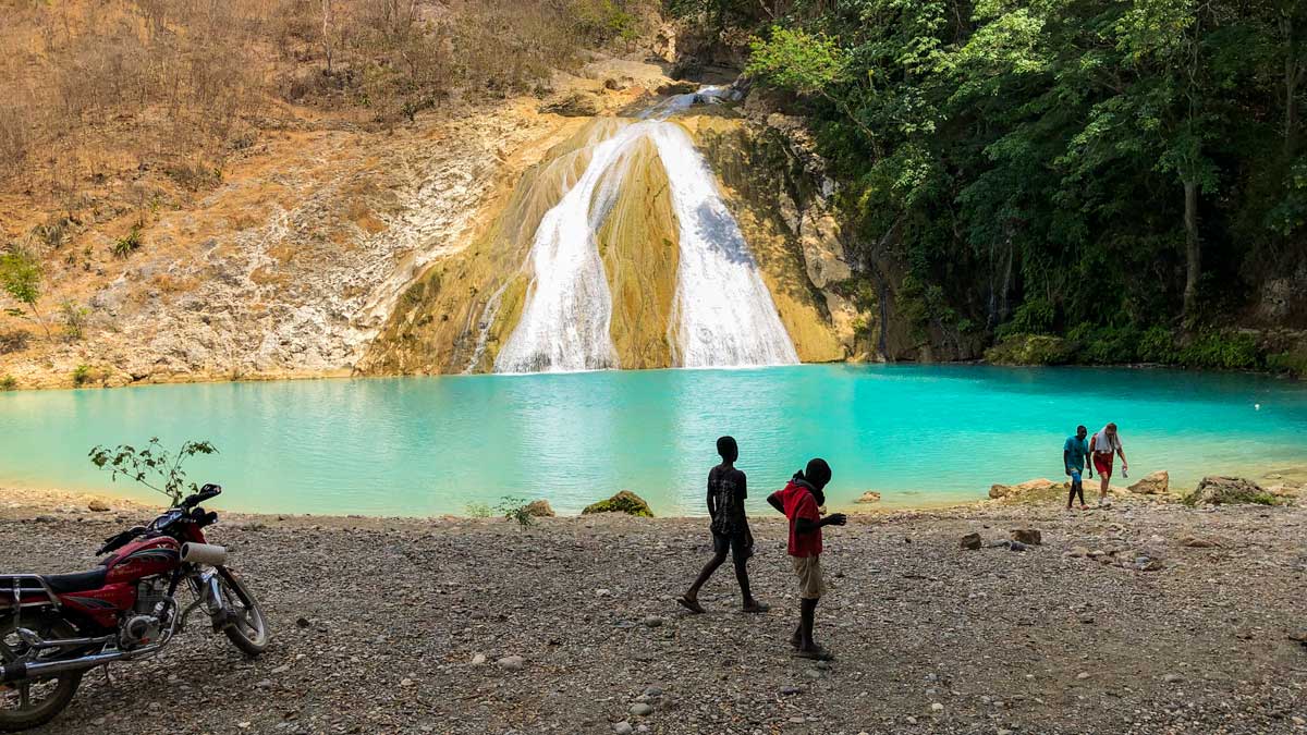 Four people and a motorbike at the shore of Bassin Zim, Haiti