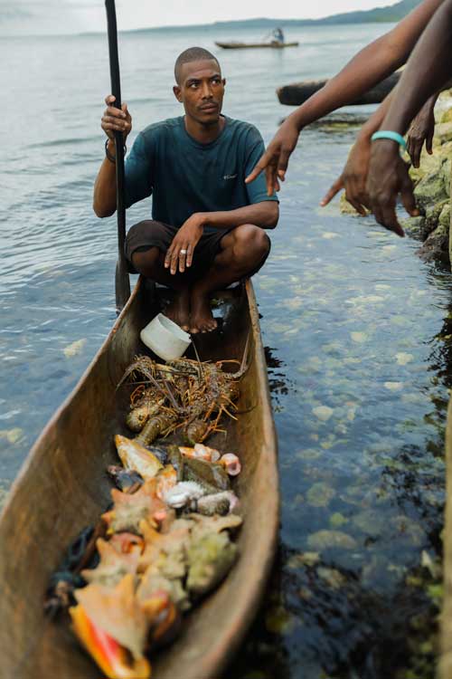 Haitian fisherman with his catch in a traditional boat near Pestel, Haiti