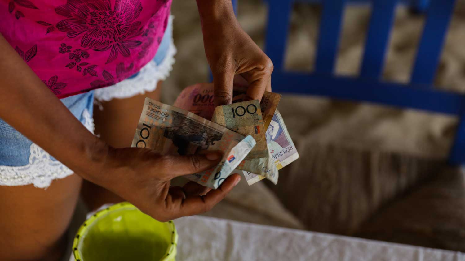 Woman holding bills of Haitian gourdes