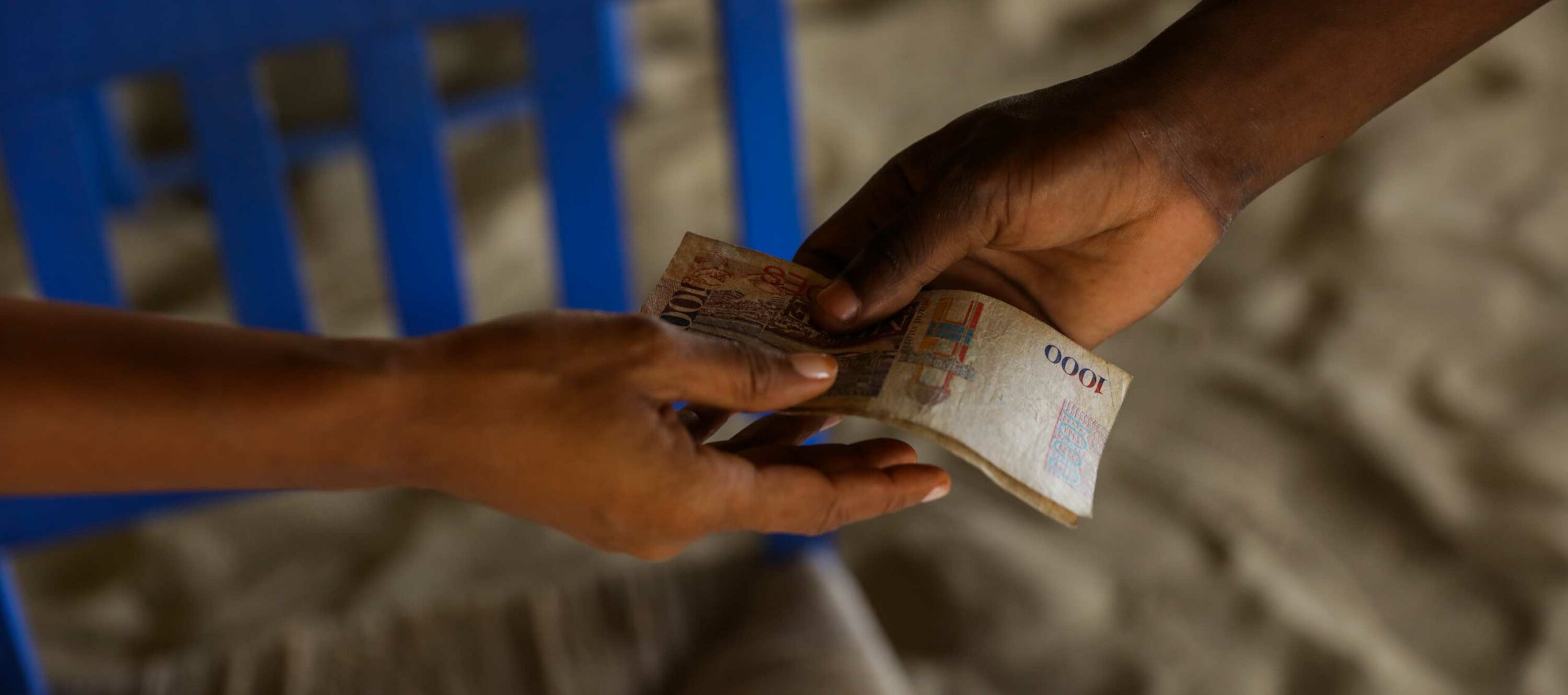 Two hands exchanging Haitian gourdes paper money