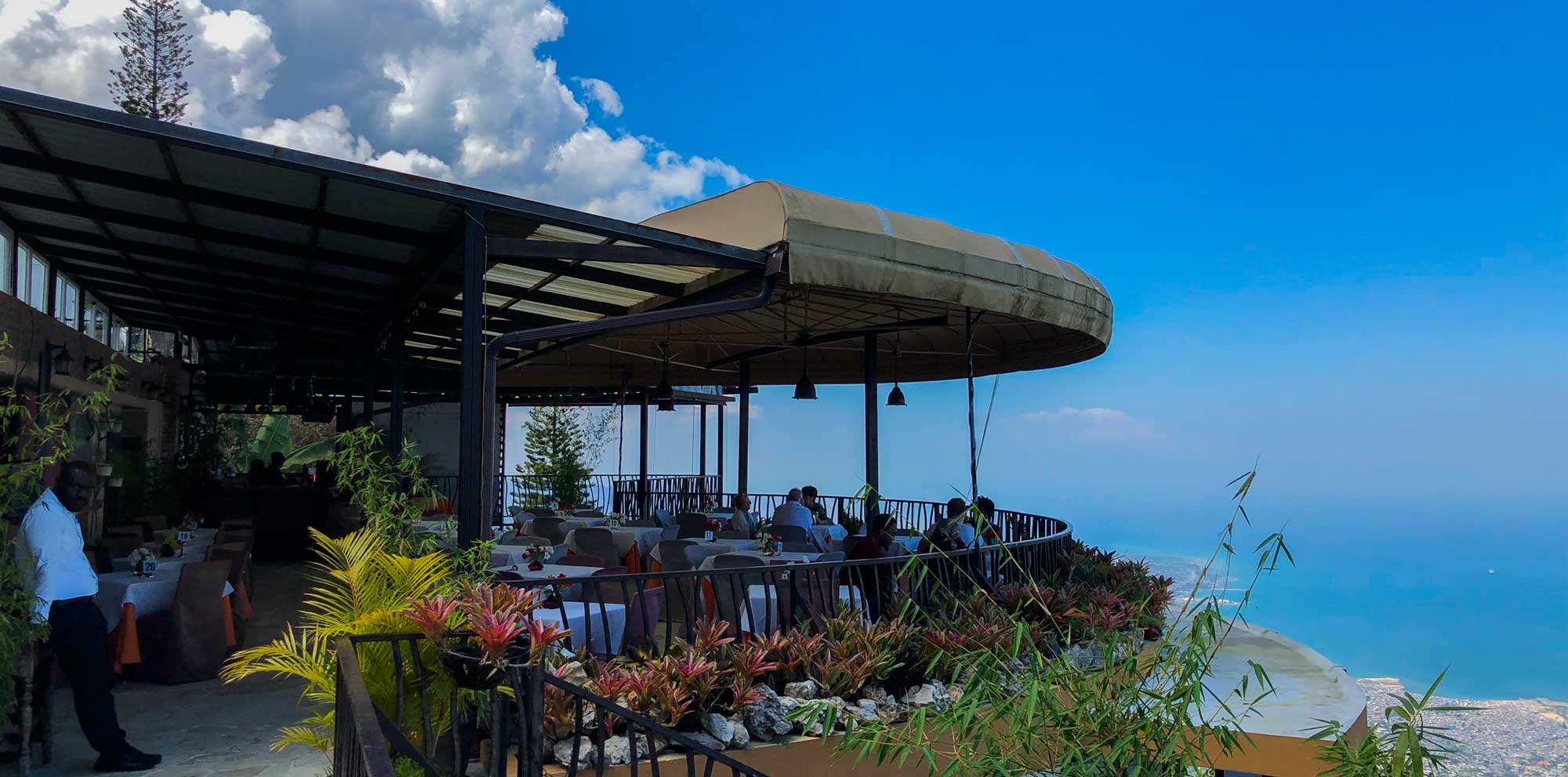 People eating lunch at L’Observatoire restaurant, Boutillier, with Port-au-Prince and the Caribbean sea in the background