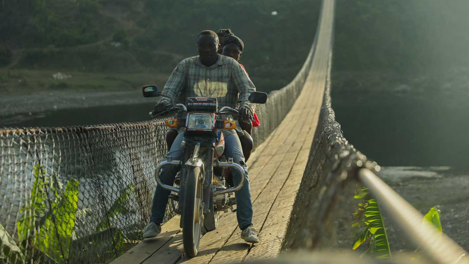 Moto driver crossing suspension bridge in Haiti