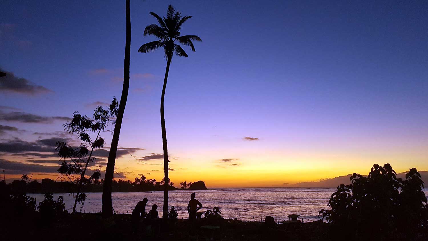 People relaxing by the sea at sunset, Haiti