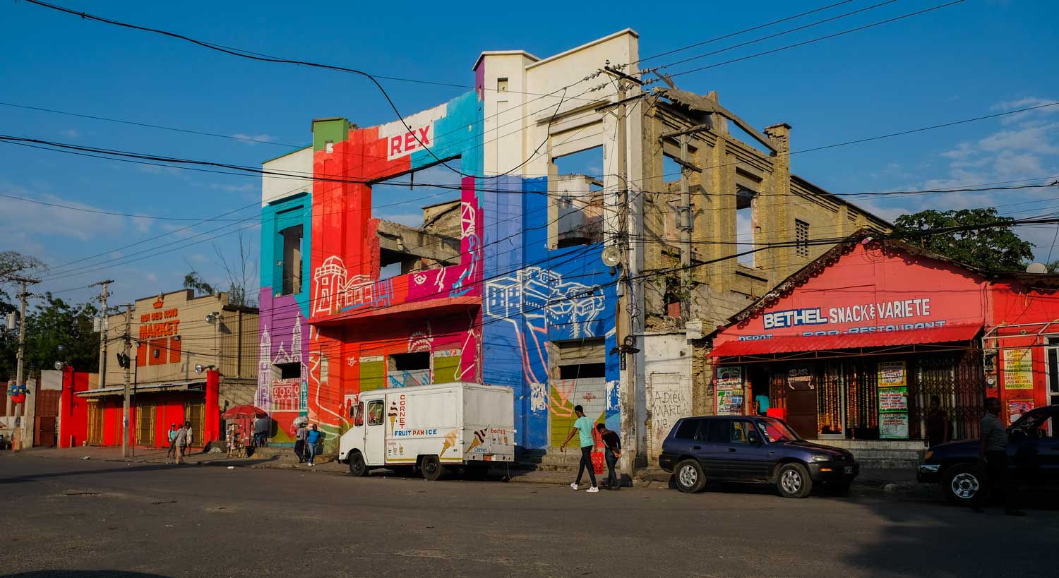 People walk past the painted, ruined facade of Rex Théâtre on Champ de Mars, Port-au-Prince