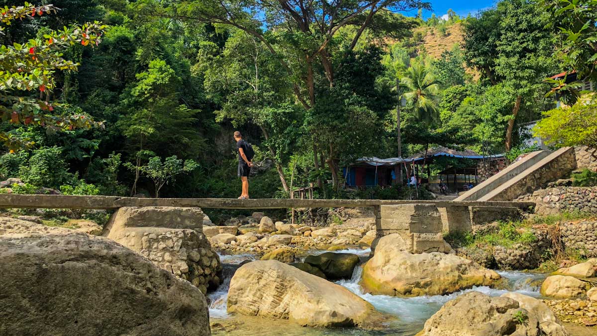 A tourist stands on a stone bridge across rapids at Gaillard, Cayes Jacmel, Haiti