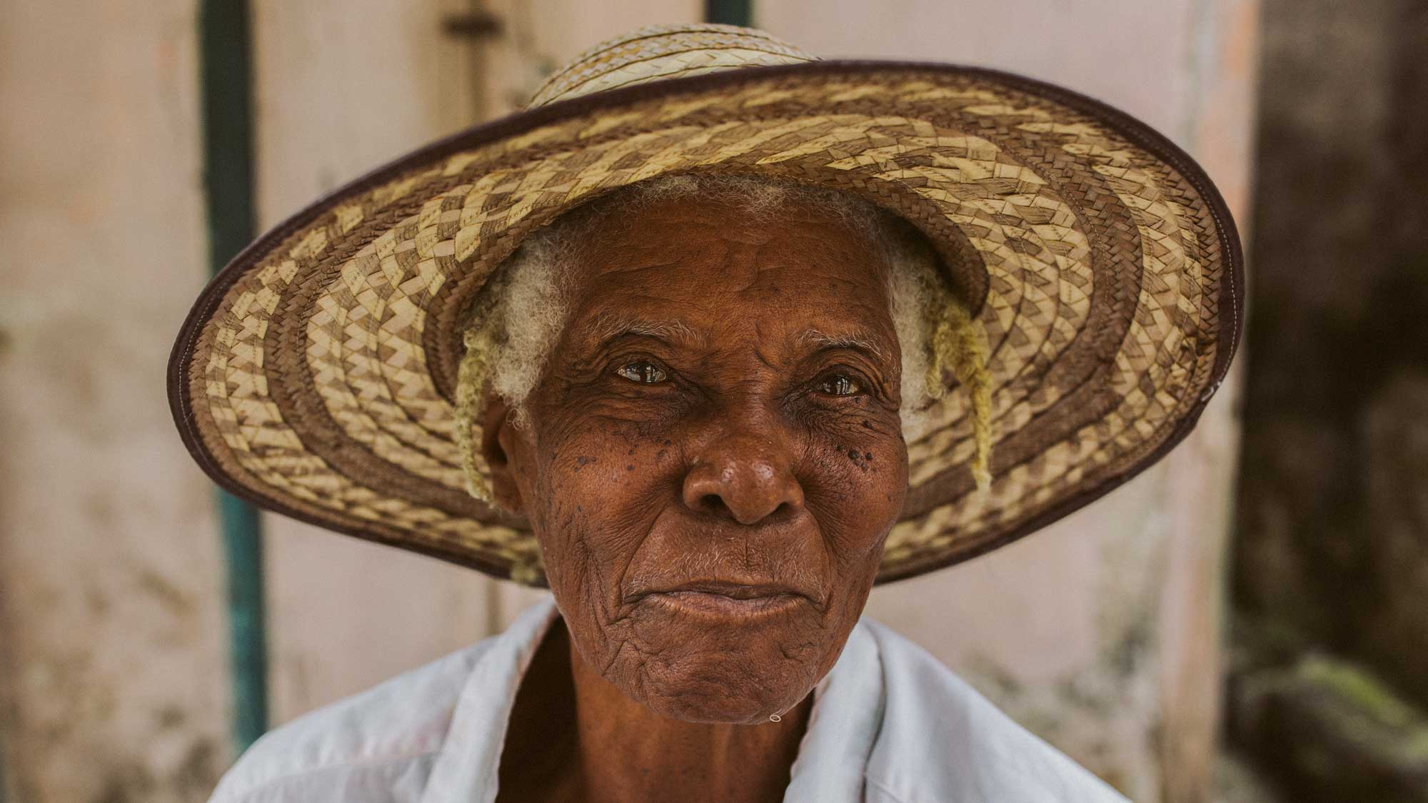 Haitian woman smiling in a straw hat, in Abricot