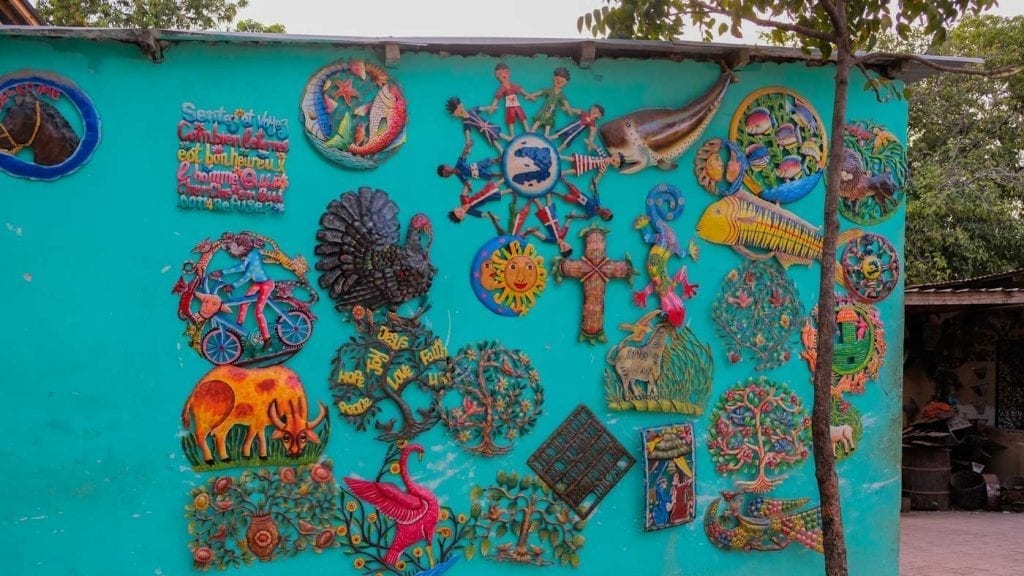 Colorful metal artwork on blue wall in Village Noailles, Haiti