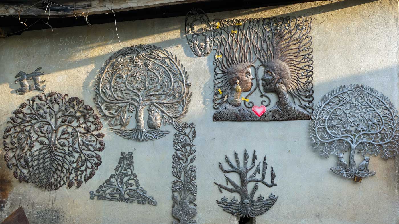 Metal artworks hang on a wall in Village Noailles, Haiti