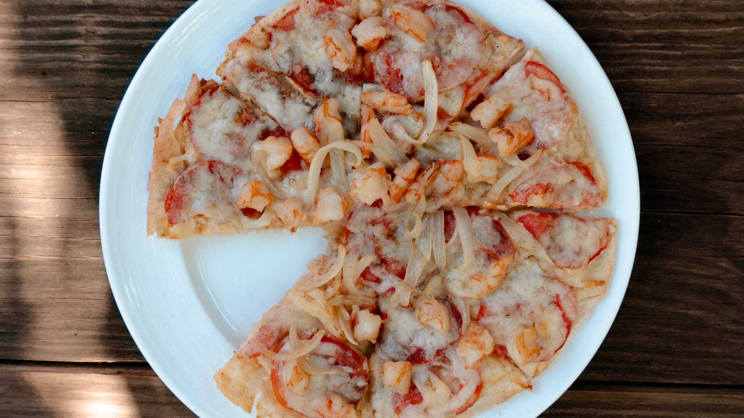 plate with pizza topped with shrimp, onions and cheese