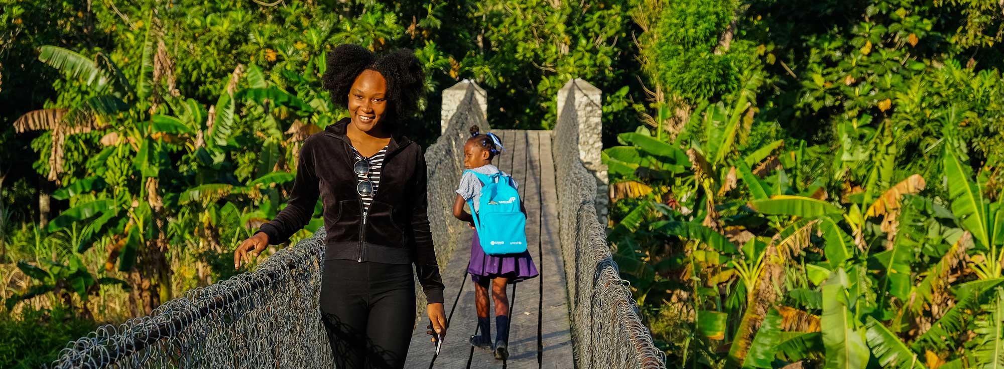 two haitians walking on small suspension bridge