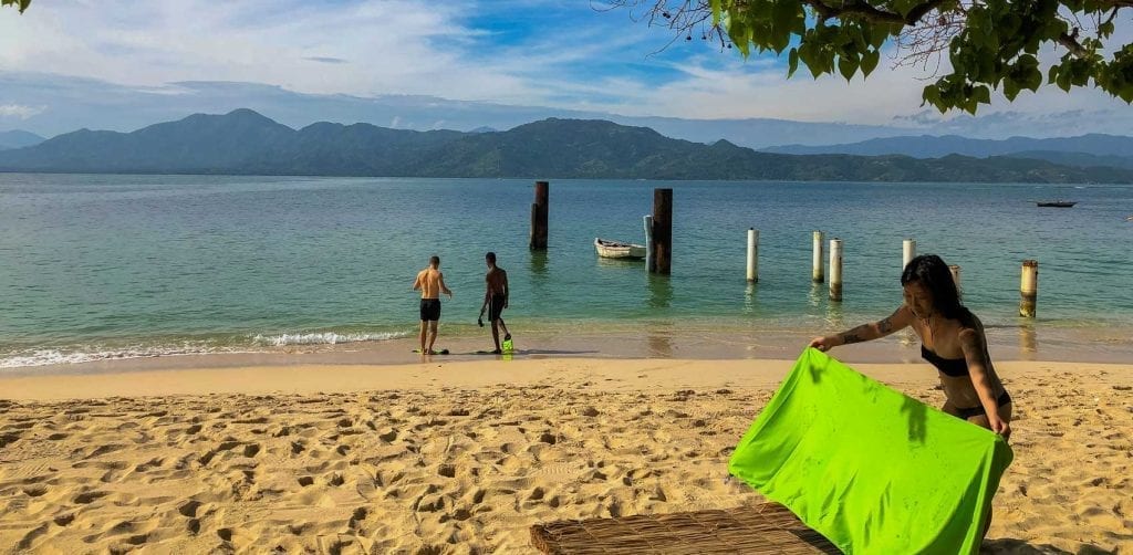 Woman throwing a towel down to relax on the beach on Amiga Island, Ile-a-rat, Cap Haitien, Haiti