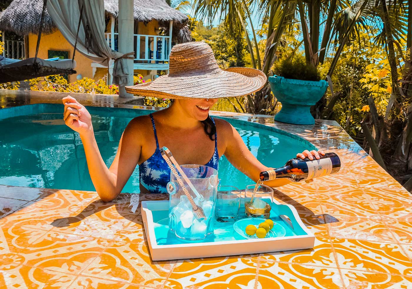 A woman makes rum cocktails while in a pool in Jacmel, Haiti