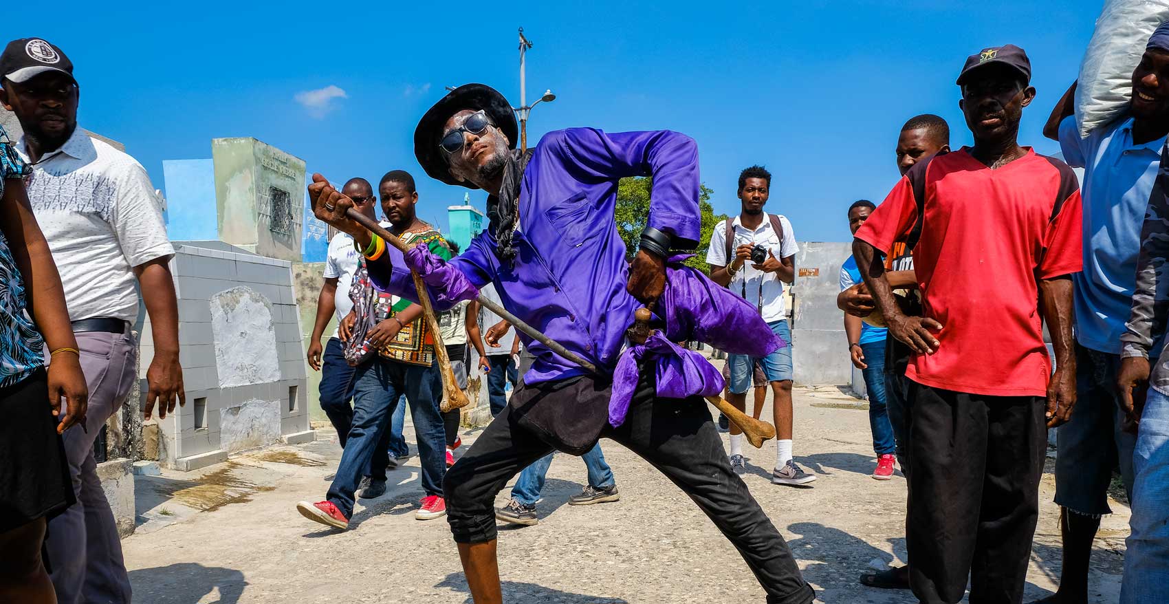 homme haïtien vêtu d'une chemise violette avec des os humains célébrant le Fèt Gede