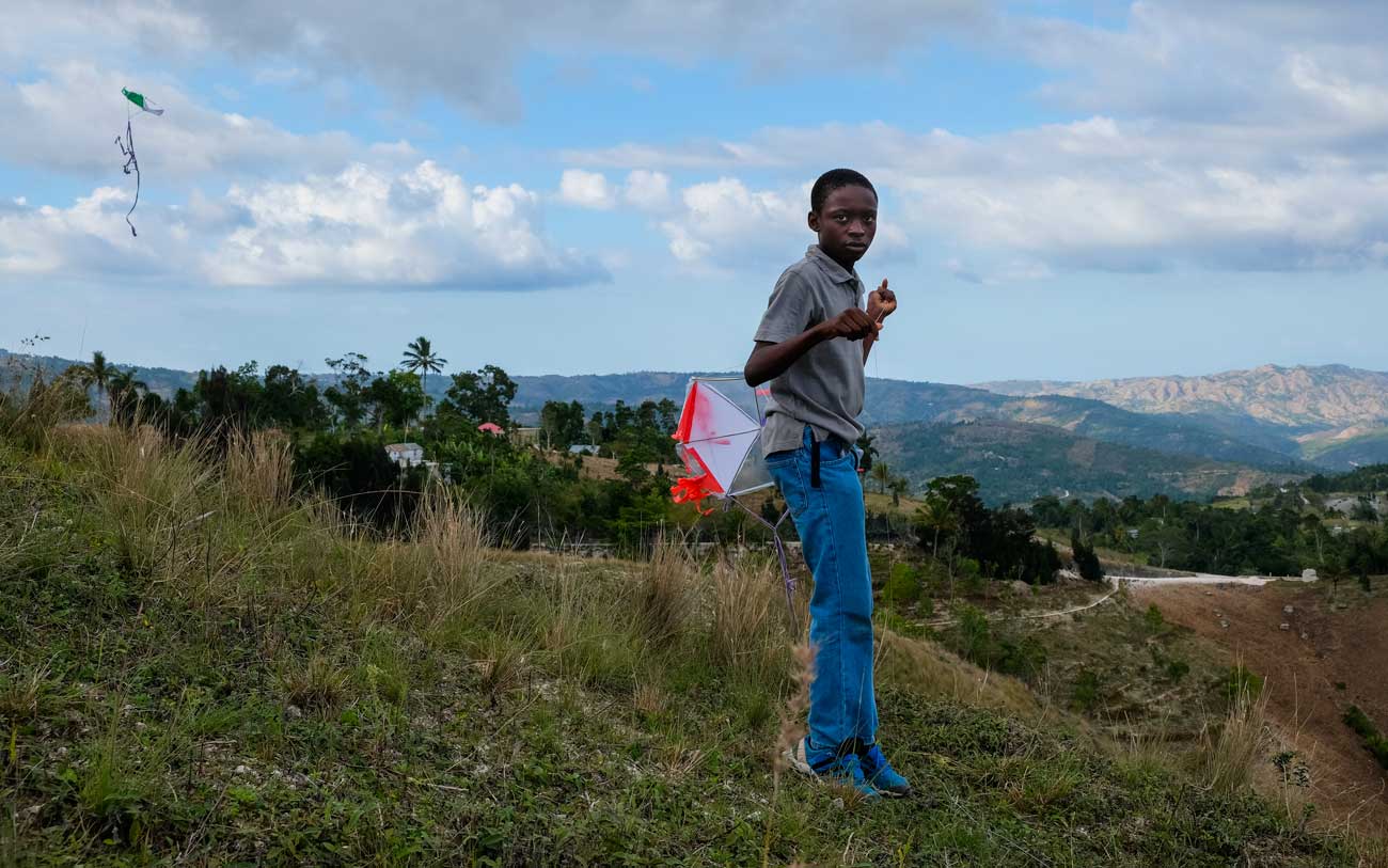 haitian boy in blue jeans with kite 