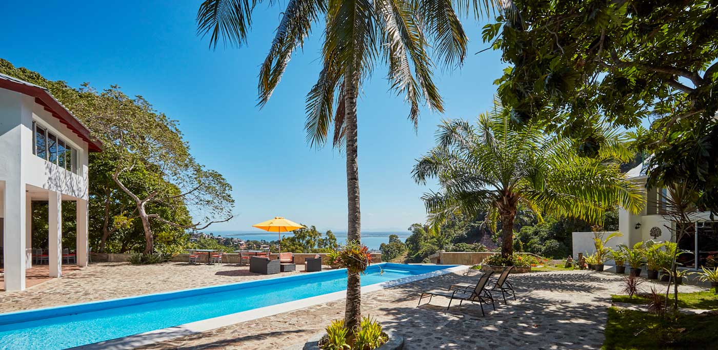 hotel area with pool, palm trees and guesthouse