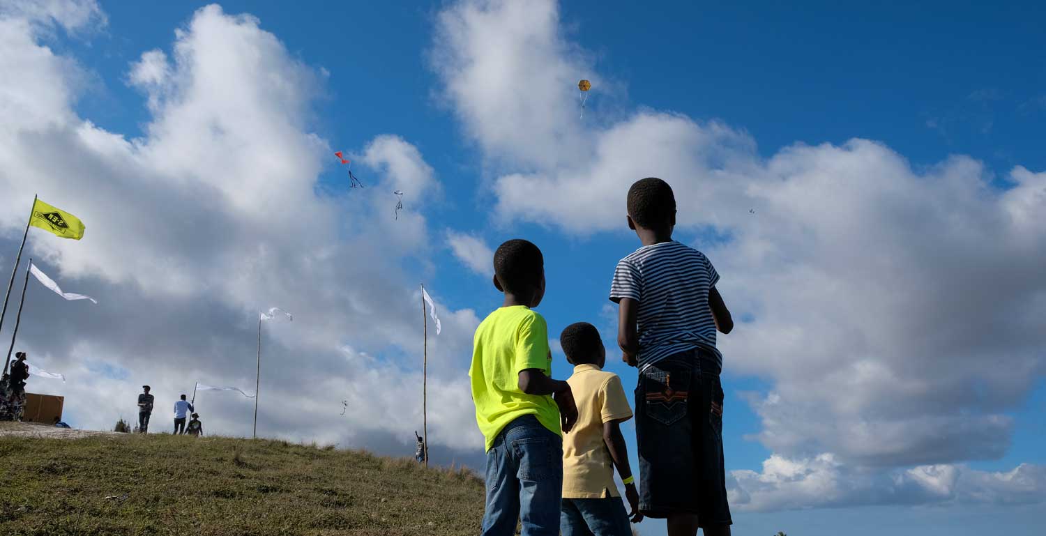 three haitian boys flying a kite