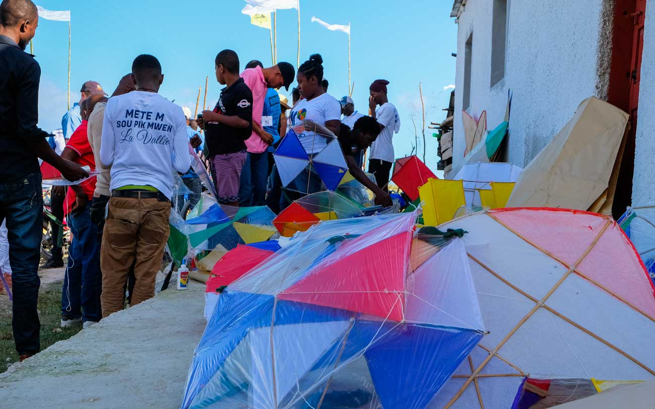 haitian stading next to kites made of plastic and bamboo