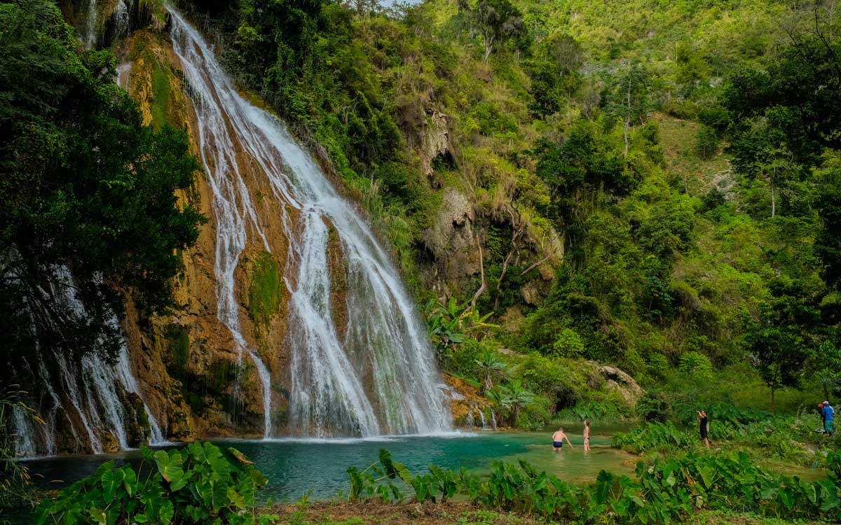 Cascada alta que cae por la ladera de la montaña hacia una piscina natural