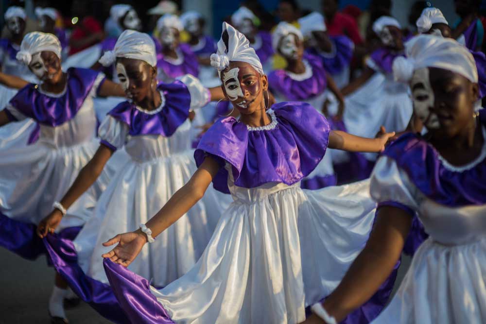 Filles haïtiennes en robes violettes et blanches avec des visages peints qui célèbrent la Fèt Gede