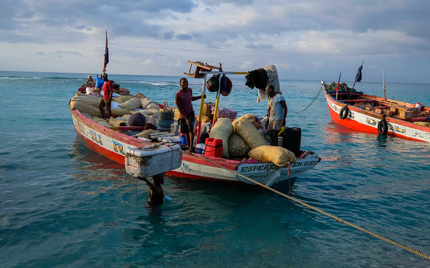 large wooden boat being unloaded by haitian men