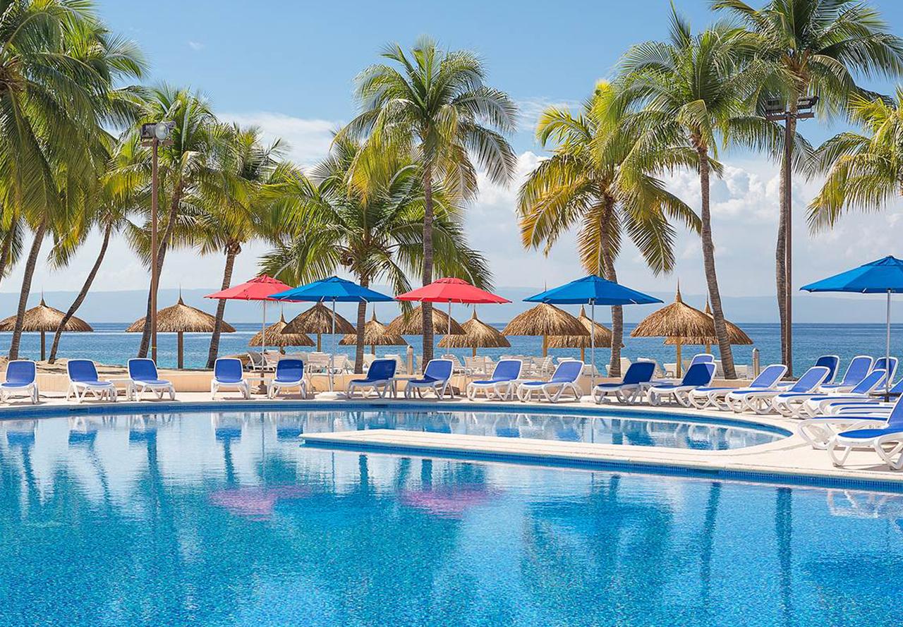 beach resort with pool, palm trees, lounge chairs and sea