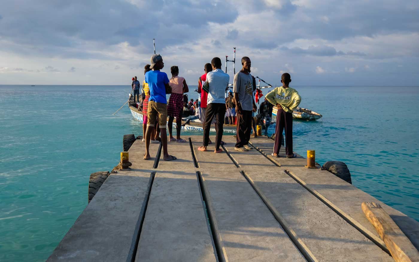 group of haitians stading on wharf with boats