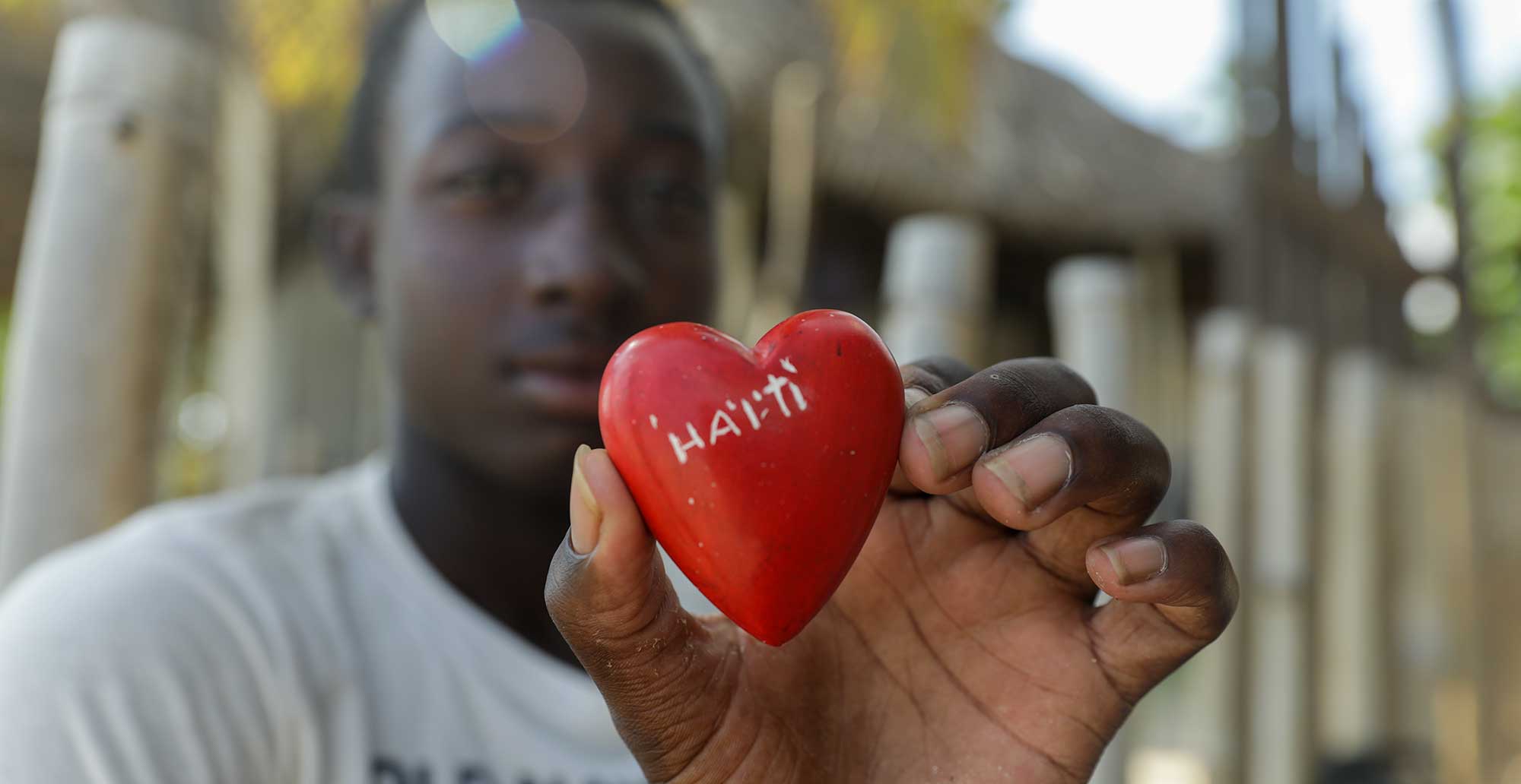 haitian boy holding a red heart carved in limestone 