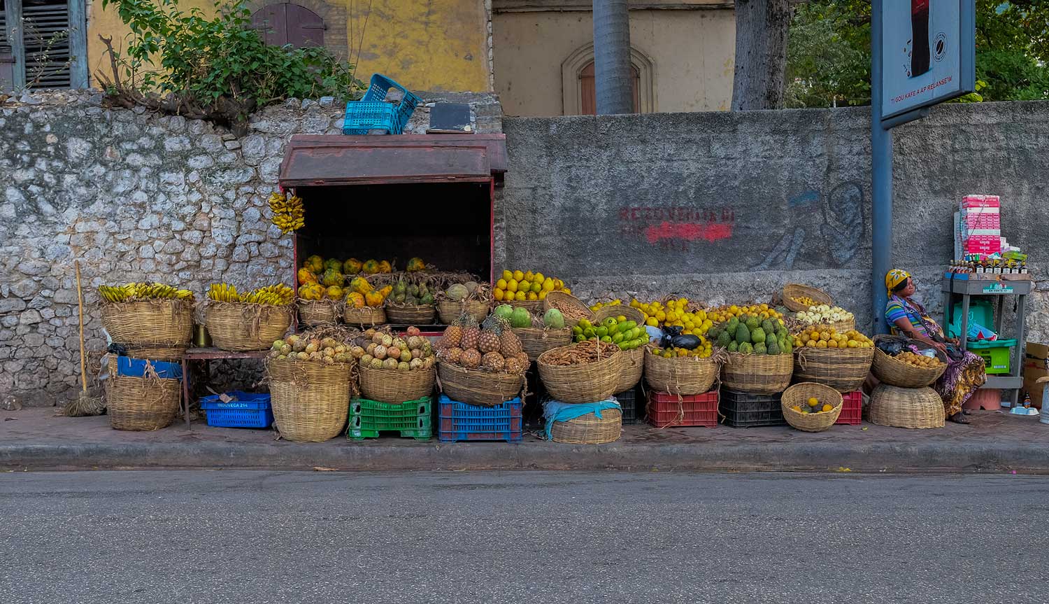 fruit vendor on city street with many straw baskets 