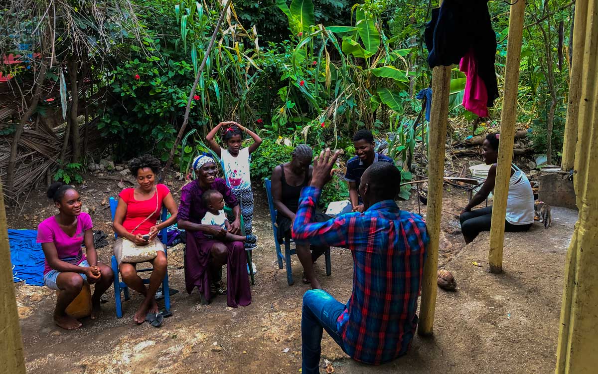 group of haitians sitting on chairs and porch in courtyard