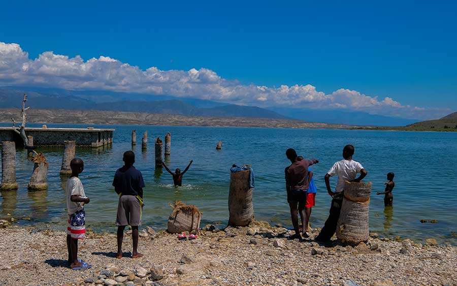 haitian boys swimming in lake surrounded by mountains