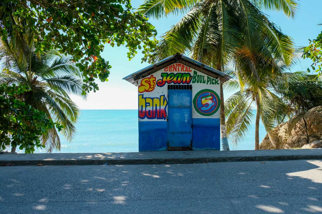 street with tiny colofully painted building with palm trees and ocean