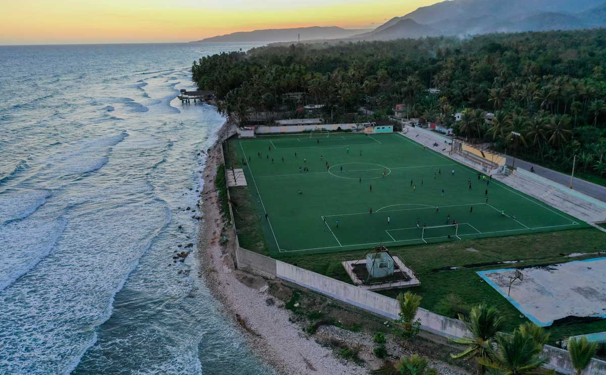 large football stadium on the haitian coast with tropical forest and mountains