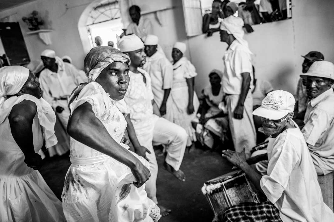 people dressed in white dancing and drumming during vodou ritual