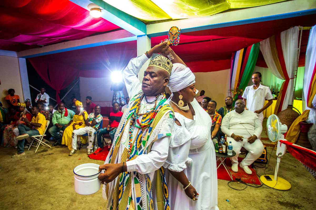 a vodou priest and practitioner performing a dance with a 