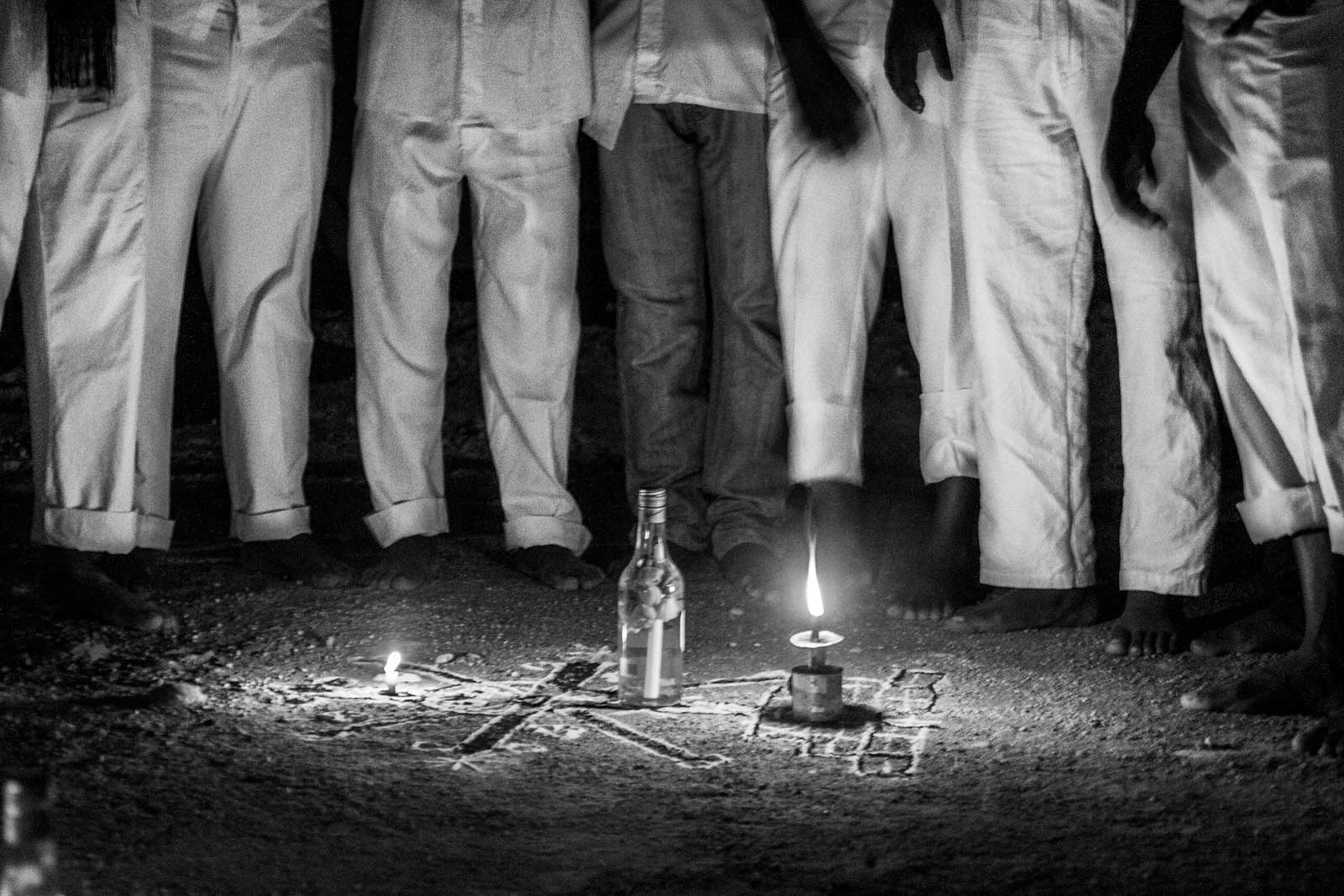 group of people standing around a candle and cosmogram drawn on floor