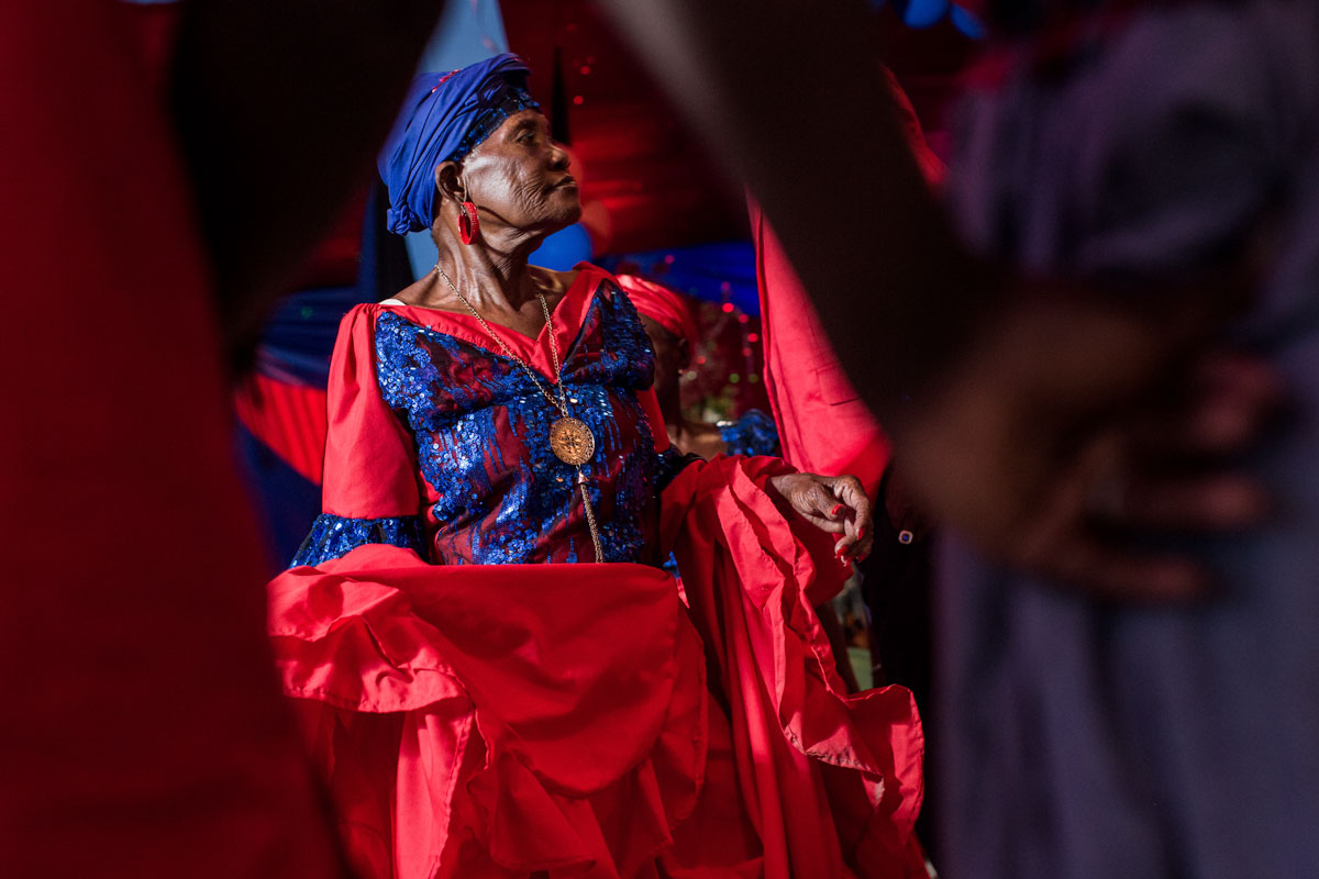 older haitian woman in a red dress with blue 