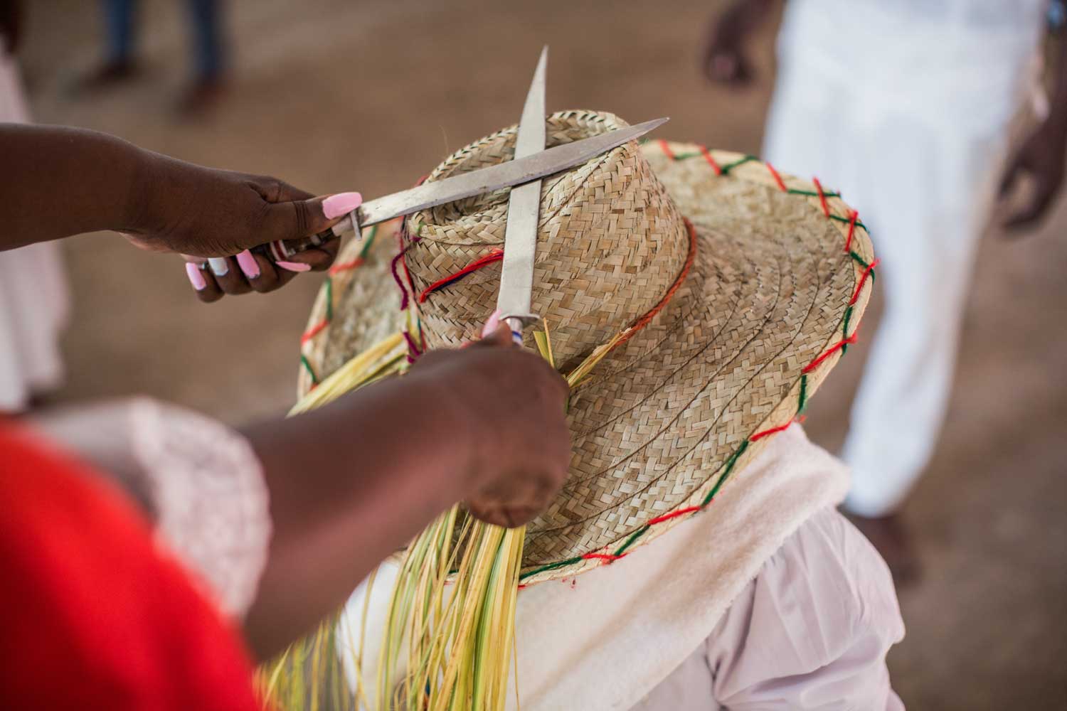 woman making a cross with two knives on a straw hat