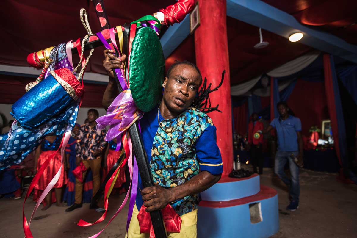 man carrying decorated cross during vodou ceremony