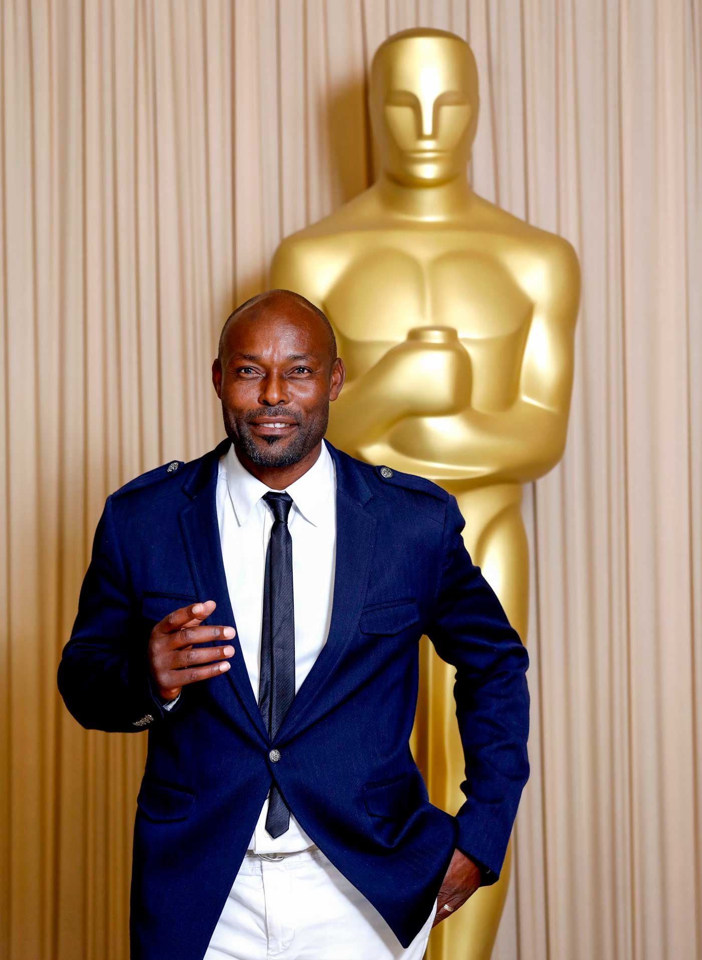 haitian actor in front of oversized golden oscar statuette