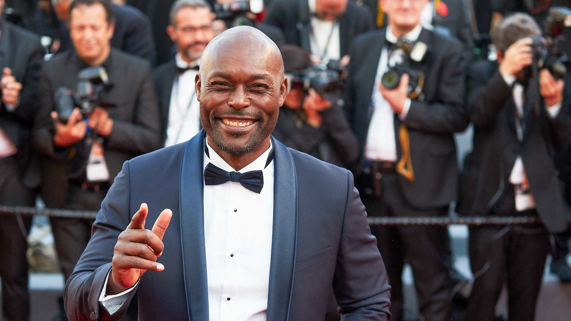 haitian actor in black suit with photographers