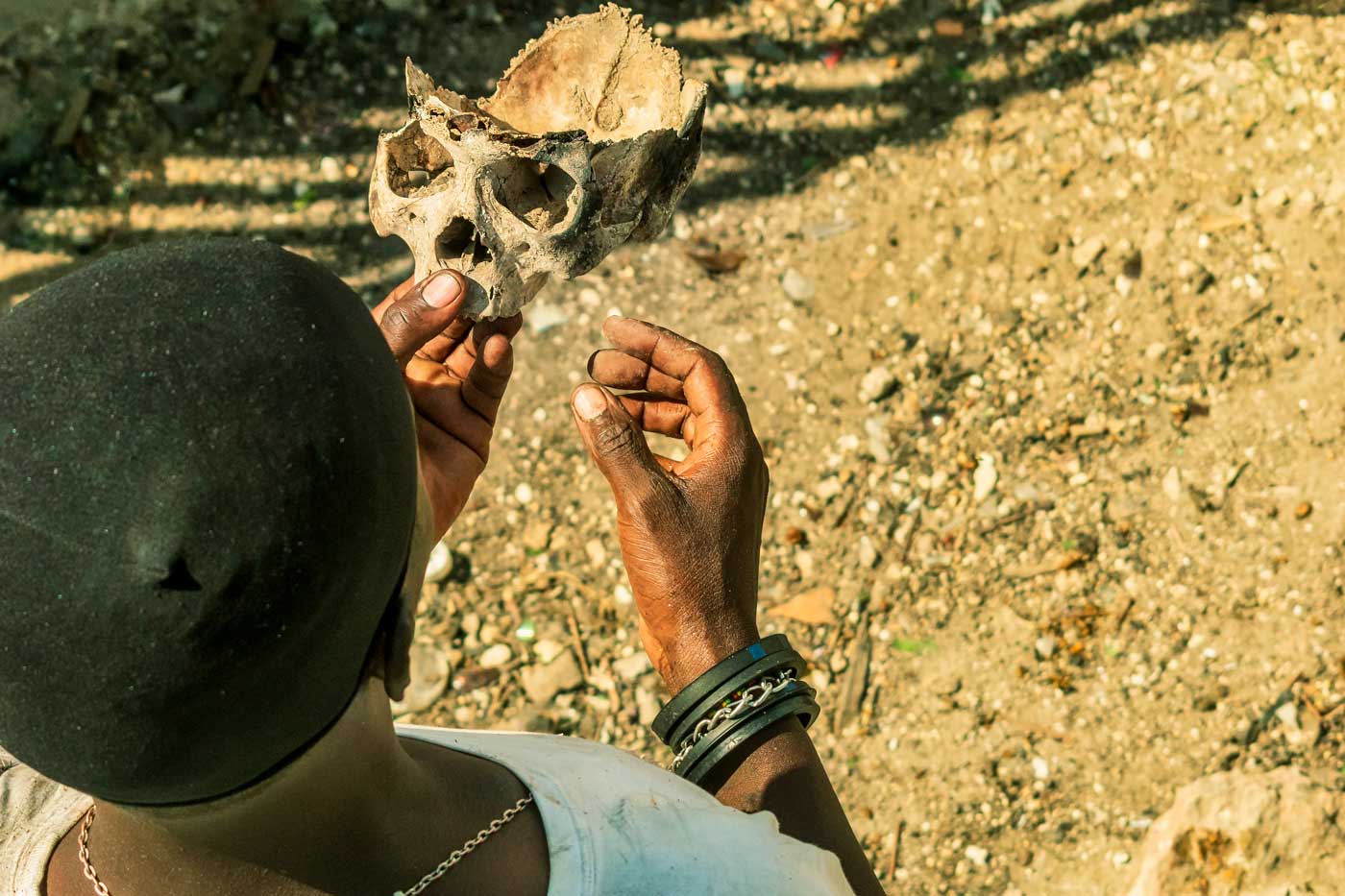 homme haïtien tenant une partie de crâne humain pour la Fête gede