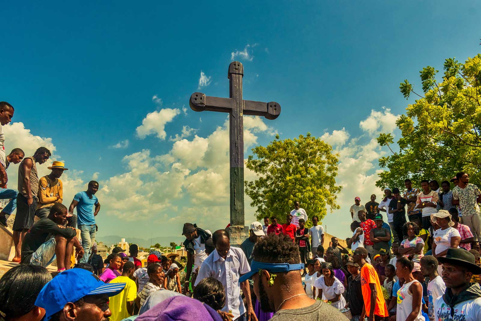 Foule rassemblée dans un cimetière haïtien avec une grande croix pour le rituel de Fèt Gede