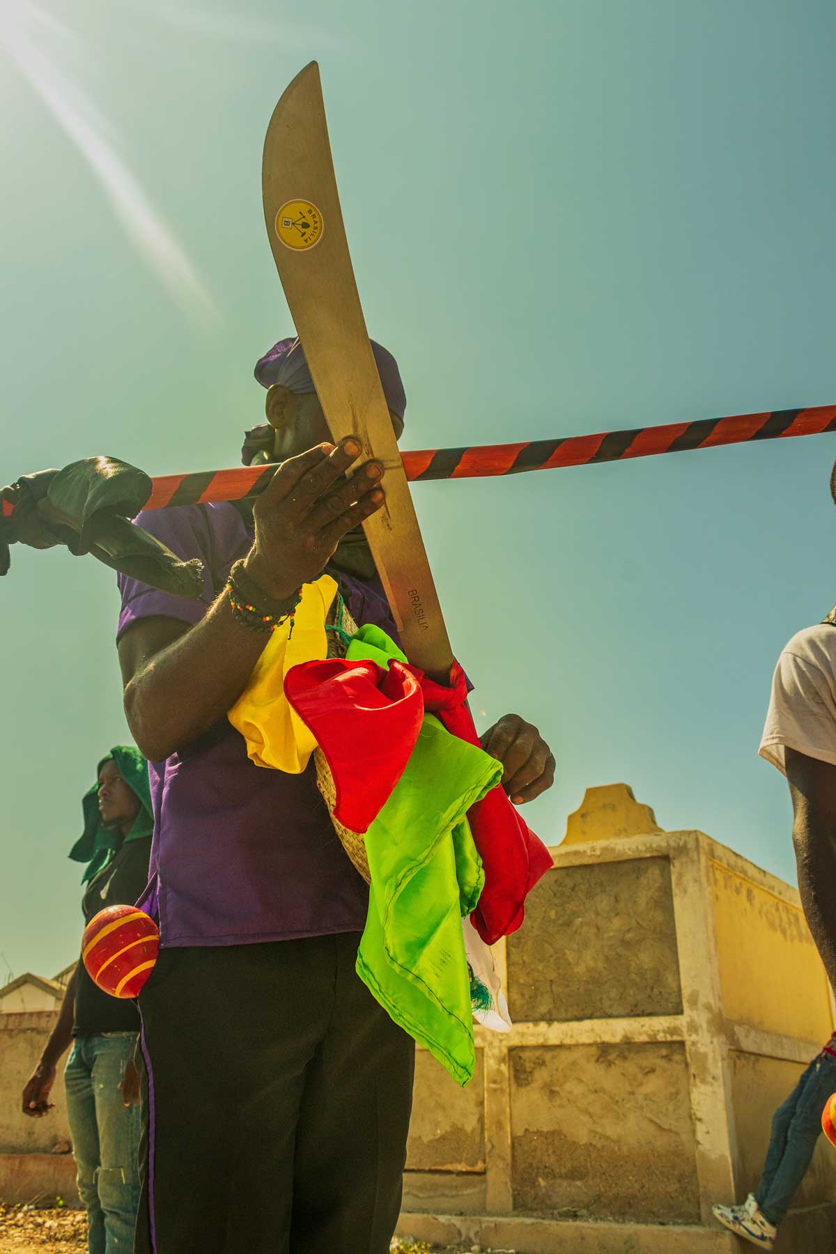 vodou practitioner holding a machete and colorful handkerchiefs