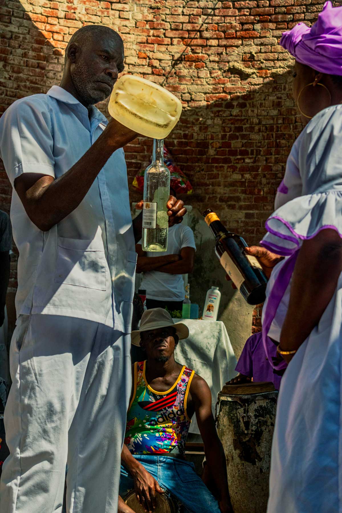 vodouisant haïtien vêtus de blanc remplissant une bouteille transparente avec un liquide