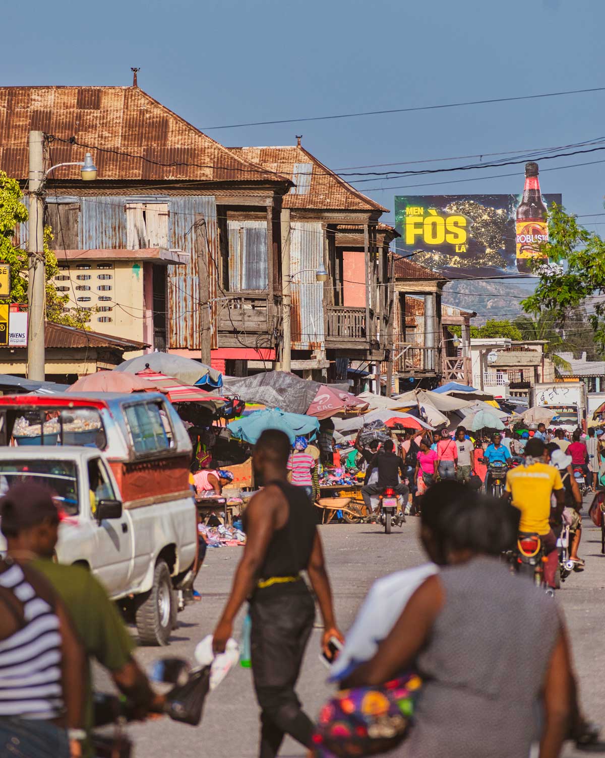 busy city street with market activity and motorcycles